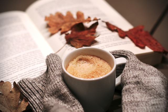 Woolens and a mug of heavily sugared coffee with leaves resting on an open book